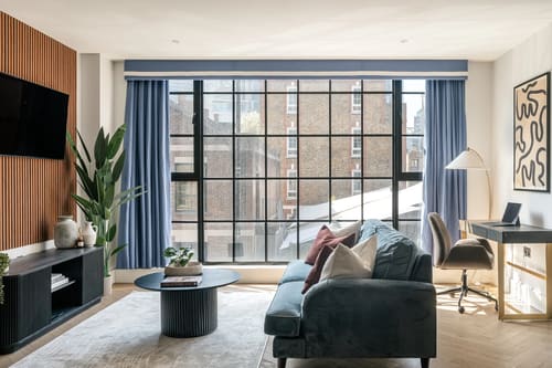The Spitalfields Urban Rest Apartments, East London: Teal sofa by tall black-framed windows