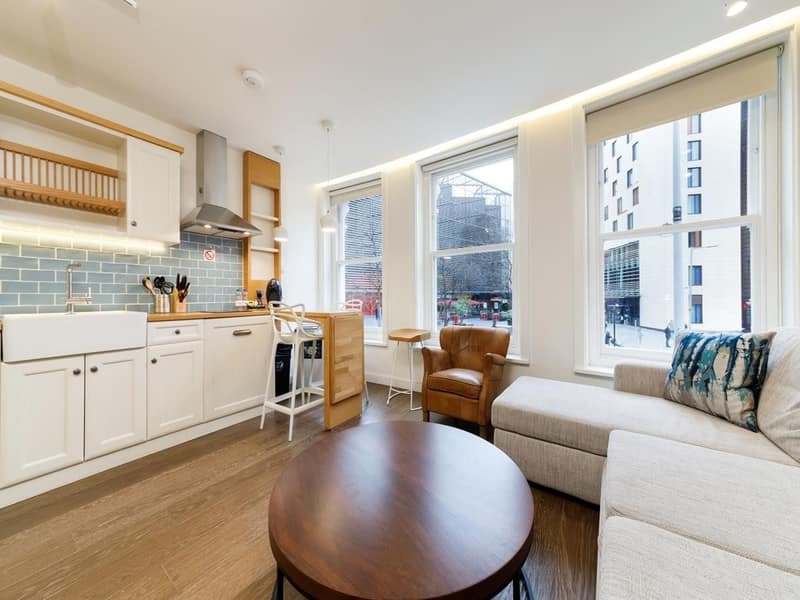 Bridge Serviced Flats, London Bridge: White kitchen with sofa beside tall windows