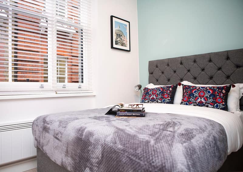 Carnaby Studios, Silver Place, Soho: Double bed beneath striped blind and pale-blue wall