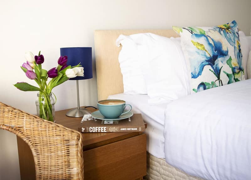 Opera House Apartments, King Street, Covent Garden: White bed beside wicker bedside table and flowers