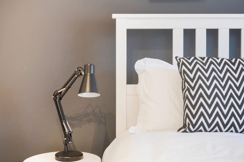 Soho Loft, D’Arblay Street, Soho: Bedside reading lamp beside a white upholstered headboard