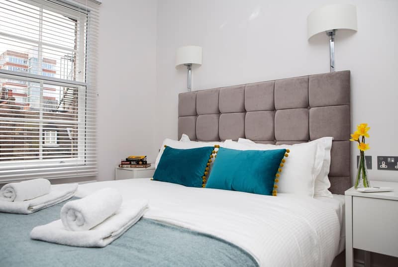 Soho Suites, Ingestre Place, Soho: White bed with teal and patterned cushions
