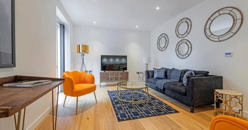 Ten On Sphinx, Battersea: Grey sofa and two orange chairs by windows