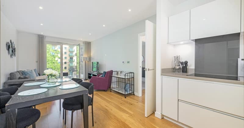 Twelve On Danvers, Battersea: Dining table and grey sofa beside balcony doors