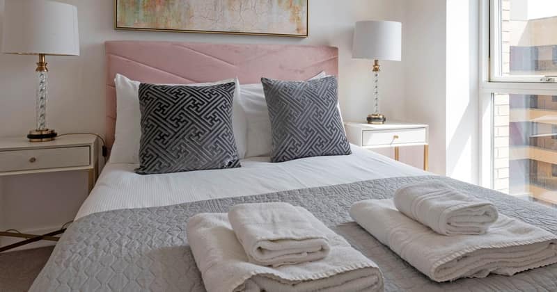 Twenty On Sphinx, Battersea: Double bed with folded towels and grey cushions