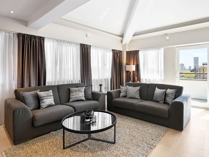 Victoria Deluxe Apartments, Victoria: Dining table and grey sofa by large windows
