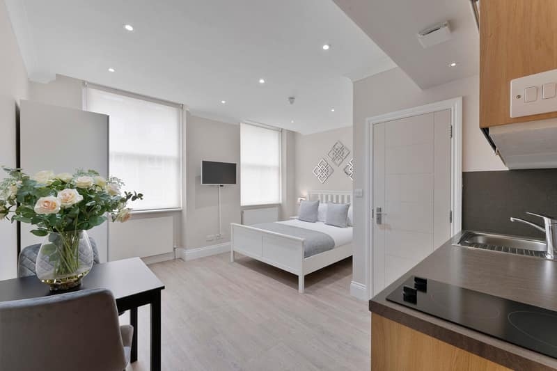 Cleveland Residences Russell Square, Bloomsbury: Living area beside white kitchen cabinets