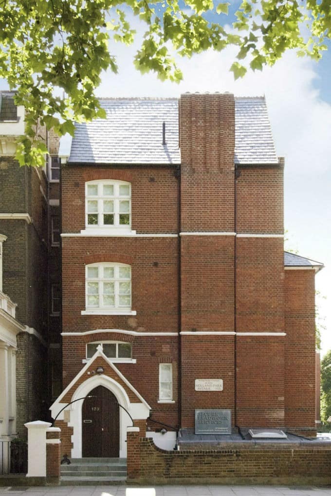 St James House, Holland Park, Kensington: Brick apartment building behind railings and mature trees