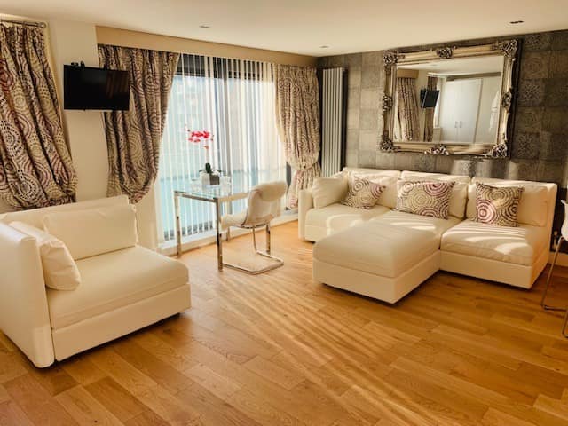 Millharbour One Bedroom Apartment, East London: Living room with cream sofas and balcony doors