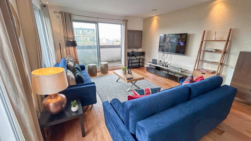 Pentonville Road Three Bedroom Apartment, King's Cross: Living room with blue sofa and dining table