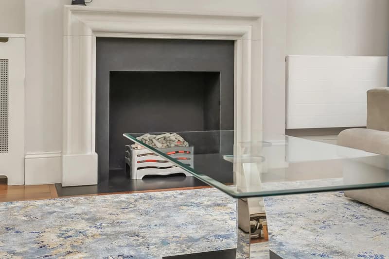 Tavistock Place Apartments, Bloomsbury: Glass table beside fireplace and upholstered chair